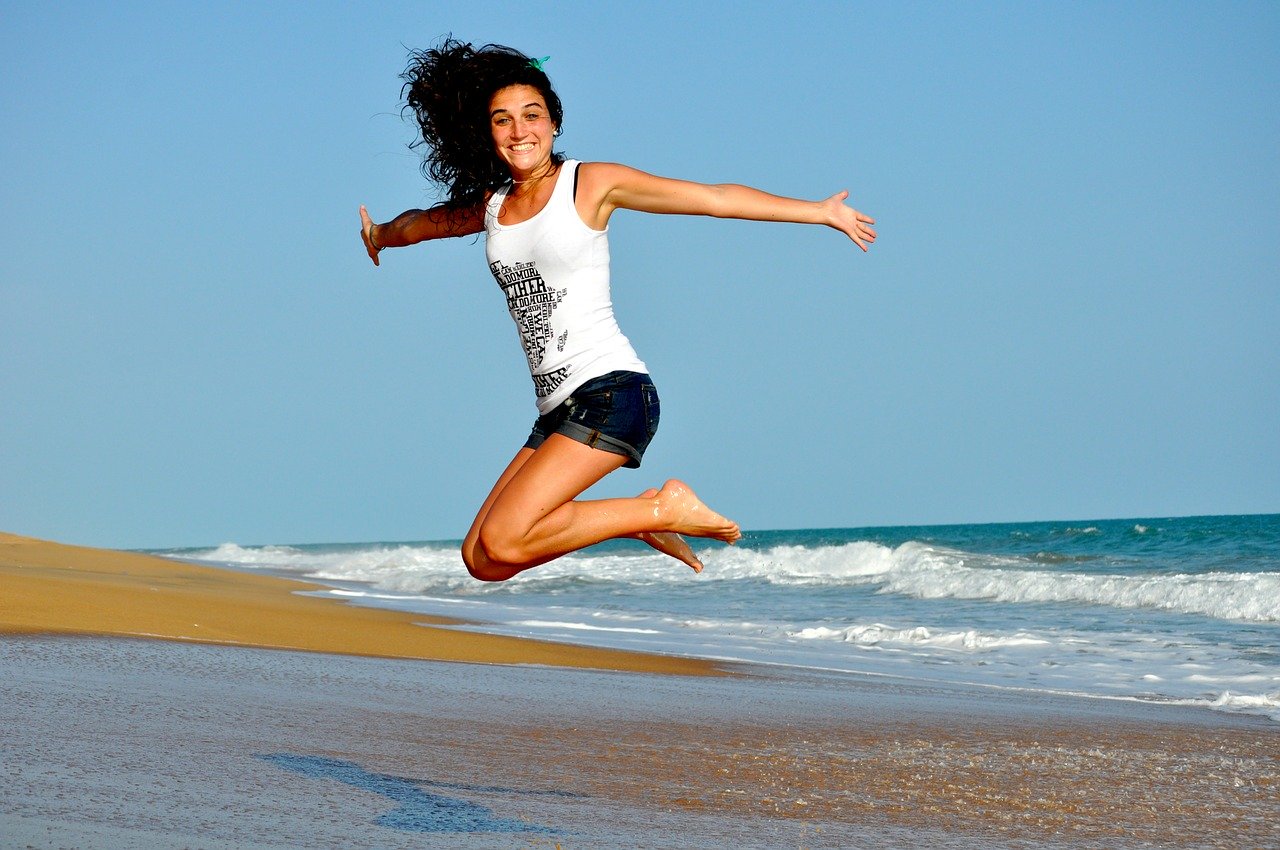 jeune femme souriante qui saute sur une plage