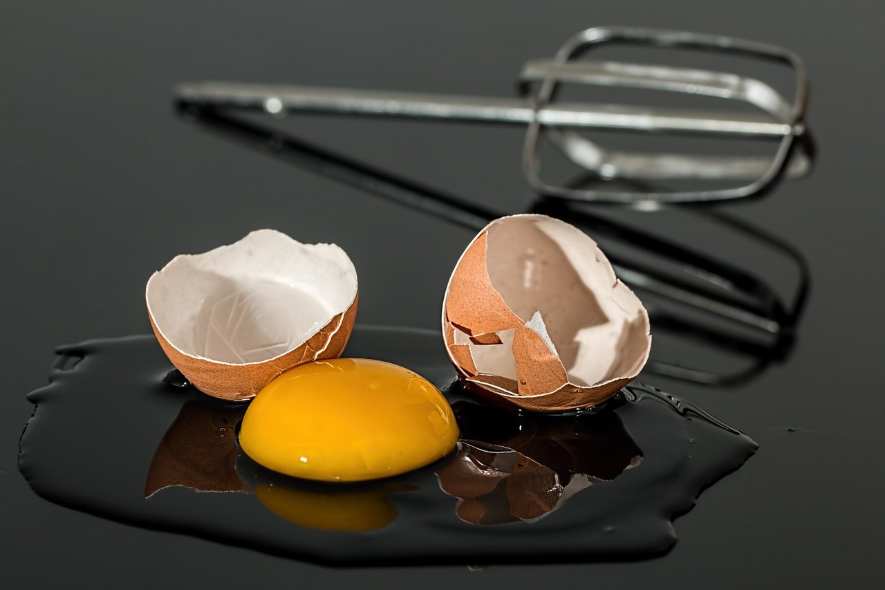 oeuf cassé sur une table et fouet